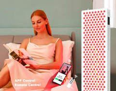 Image showing woman reading a book with a smartphone and remote control, next to a Red Light Therapy Panel. It is a great value LED purchase.