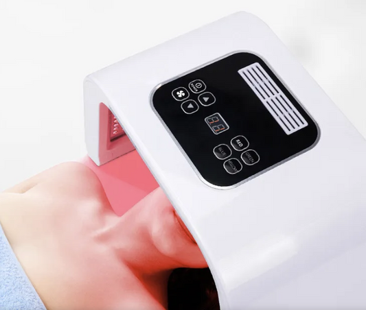 A person's face is being treated with a handheld 7-color photon skin rejuvenation device, which is white with a digital control interface. It is an ideal LED light device purchase.