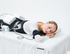 Woman lying on a white bed with a medical device 'Wonder'. It is a great value EMF and RF laser purchase.